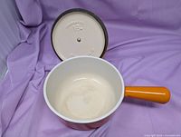 Top view of saucepan interior and lid underside showing cream enamel, stamp 16