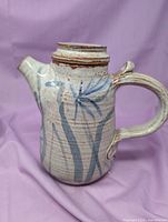 Left profile of stoneware teapot showing handle, spout and blue foliage design