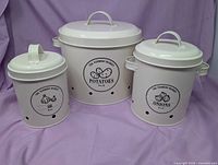 Set of three nested off-white metal canisters with lids, showing English labels and vent holes