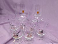 All eight glasses grouped: 2 Cowbell beer, 6 Baileys liqueur