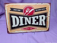 Front of metal DINER sign showing graphic and faux aging