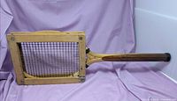 Full view of racket secured in wooden press