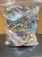 Front view of sealed bag showing tangled mix of necklaces, bracelets, beads and metal chains