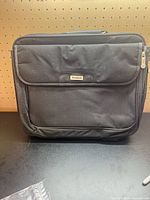 Front view of closed Targus black briefcase showing exterior pocket and logo plate
