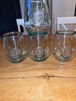 Four aqua-tinted stemless wine glasses with embossed medallion logo