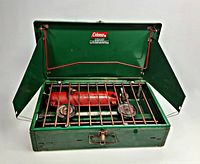Coleman 413F stove open showing grate, burners, fuel tank installed