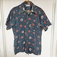 Front view of blue short-sleeve button-down shirt on hanger, showing overall print and collar