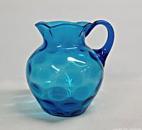 Front view of blue glass pitcher showing optic pattern and handle