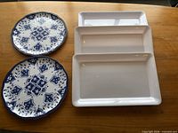 Two blue floral plates and three white rectangular platters on table