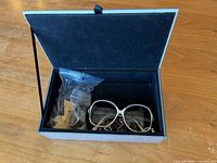 Storage box open showing sunglasses and bag of loose parts