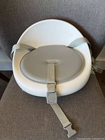 Front/top view of gray and white Skip Hop booster seat showing seat pad and front safety strap