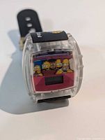 Front view of digital watch showing clear case and Simpsons family graphic on face