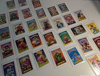 Overhead view of roughly 30 sleeved Garbage Pail Kids cards spread on table