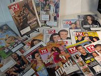 Overhead view showing multiple sealed TV Guide issues laid out, identifiable covers visible