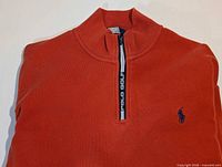Front view of orange quarter-zip pullover showing collar, zipper, logo