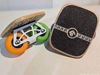 Top and side view of both freeskates showing wood deck, black grip, white truck and multicolour wheels