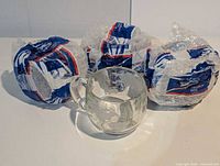 Four mugs, three wrapped in bubble wrap, one unwrapped on display