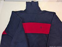 Full back view showing navy body, red stripe, turtleneck collar