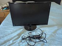 Front view of AOC monitor on stand with power adapter and cable