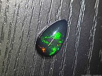 Pear-shaped black opal showing green and red fire