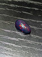 Black opal cabochon showing red and blue play of colour