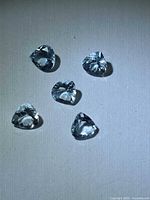 Five light blue aquamarine stones on white surface