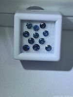 Front view of 11 round blue sapphires in display box