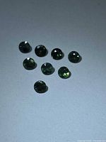 All eight round green sapphires arranged on neutral background