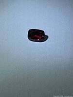 Loose cherry red cushion-cut garnet on neutral background