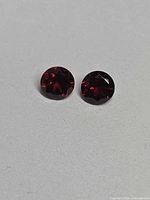 Pair of round red garnets on white background