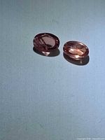 Two oval pink-orange spinels on neutral background