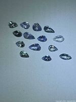Group of 13 pear and marquise cut violet-blue Tanzanite gemstones on light background