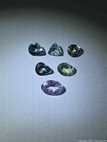 Six faceted Tanzanite stones displayed under light