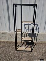 Front view of black metal shelf showing five staggered shelves