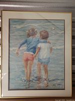 Front view of signed framed print showing artwork of two children at beach