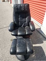 Front view of black leather recliner with ottoman