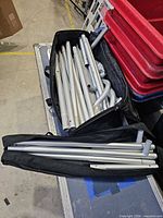 two carry bags filled with silver aluminum poles and connectors