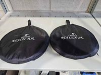 two folded reflectors in branded black pouches