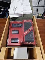 Box opened showing shrink-wrapped Digitech XP100 pedal, manual, power adapter