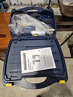 Hammer drill, accessories and manual inside open carrying case