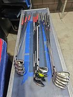 Full set of 13 clubs laid out, showing irons on right and woods/hybrids in middle