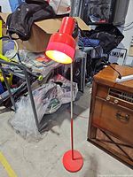 Full view of red metal floor lamp showing base, stem and shade