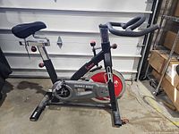 full side view of spin bike showing frame, flywheel, seat