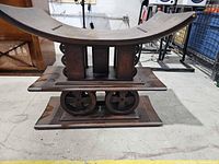 profile view showing curved saddle seat and stacked base with circular carvings