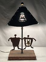Full view of lamp showing shade illuminated, steel figures, sandstone base