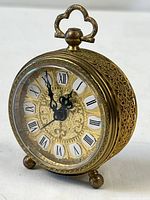 Front angled view of clock showing filigree case, feet, loop and dial