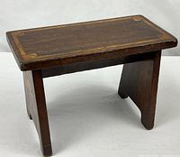 Three-quarter view of footstool showing top, legs, stretcher and inlay