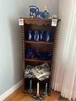 Full shelf view showing glassware, ceramics, linens and candles