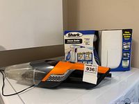Bissell handheld vacuum and boxed Shark steam cleaner side by side