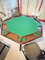 Octagonal card table top with green felt surface drink holders and chip trays chairs visible